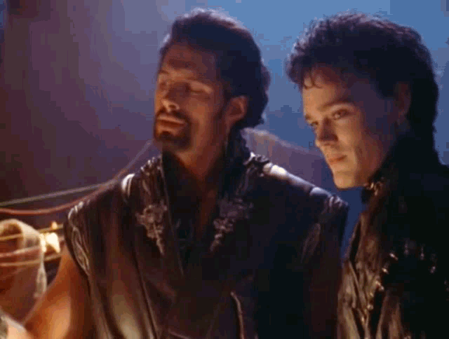two men are standing next to each other in a dark room looking at each other .