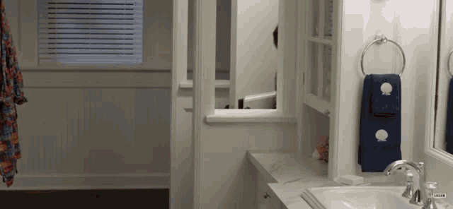 a bathroom with a sink and a window with a towel hanging from it