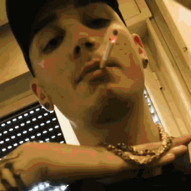 a man is smoking a cigarette and wearing a gold chain