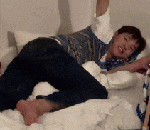 a person is laying on a bed with their arms in the air
