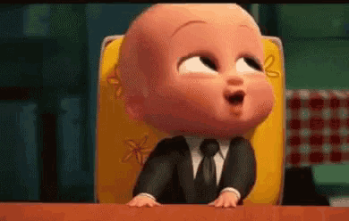 a cartoon baby in a suit and tie is sitting at a table .