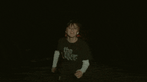 a man is playing drums in a dark room with a light behind him