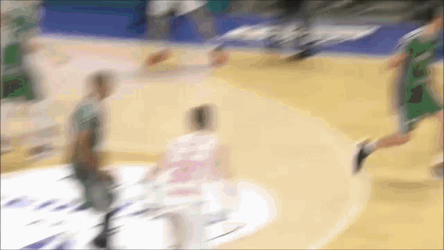 a blurry picture of a basketball game with a few players in green and white jerseys