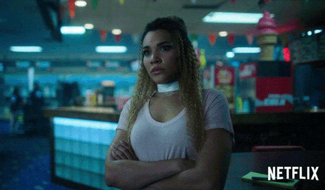 a woman is sitting at a table with her arms crossed and a netflix logo in the corner