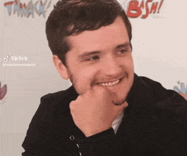 a man is smiling with his hand on his chin in front of a sign that says bsw