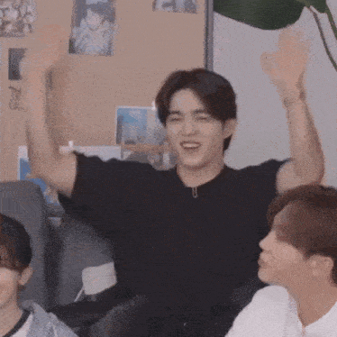 a man in a black shirt holds his arms up in the air