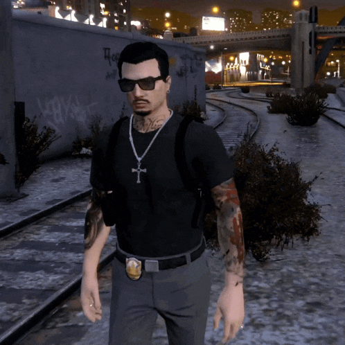 a man wearing sunglasses and a cross necklace stands in front of a wall with graffiti
