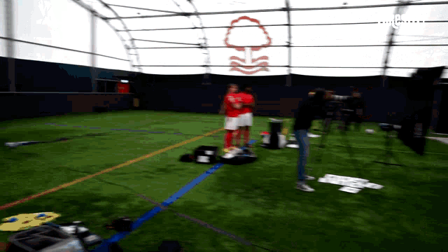a man in a red shirt stands on a soccer field in front of a sign that says england