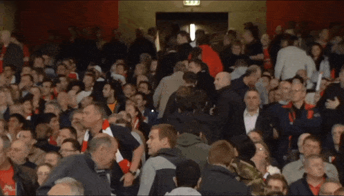 a crowd of people are gathered in a stadium with an exit sign