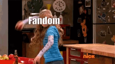 a girl in a blue shirt is dancing in a kitchen with the word fandom written above her