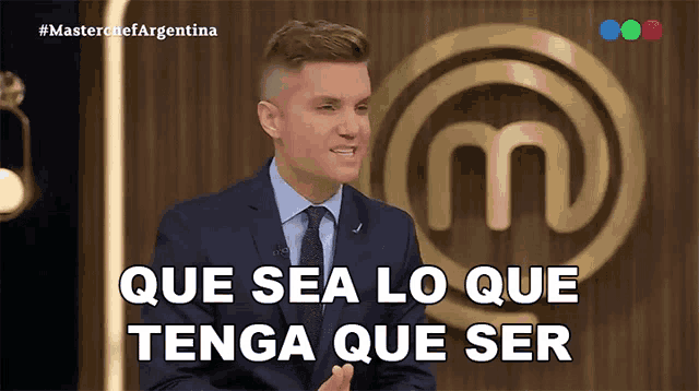a man in a suit and tie is sitting in front of a masterchef logo