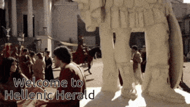 a group of people standing around a statue with the words welcome to hellenic herald written on the bottom
