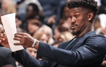 a man in a suit is reading a piece of paper .