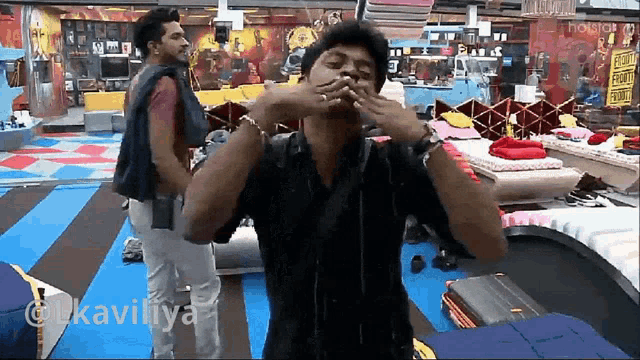 a man covering his mouth with his hands in front of a sign that says ' hotstar '