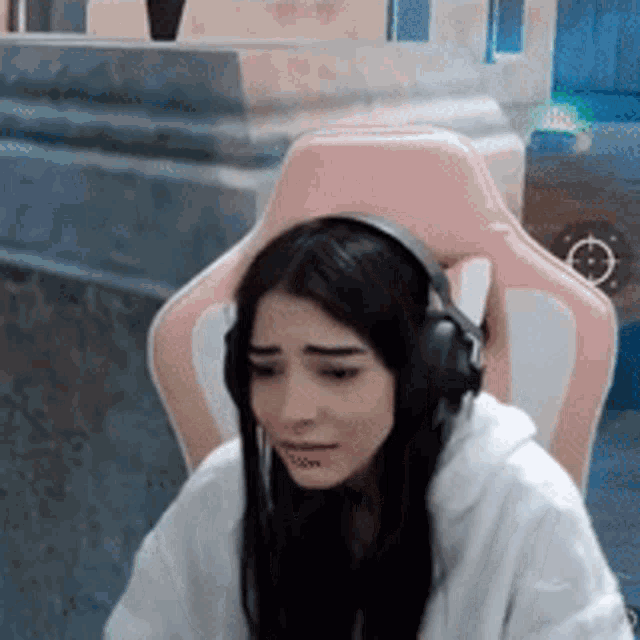 a woman is wearing headphones while sitting in a pink chair .