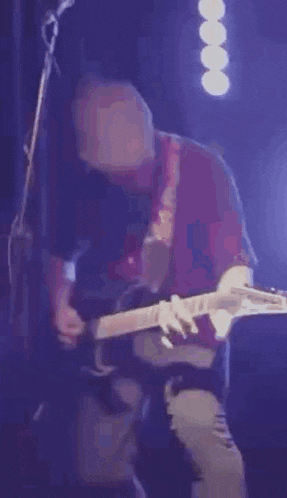 a man is playing an electric guitar on a stage in front of a microphone .