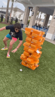 a man is jumping over a stack of orange blocks on a grassy field .