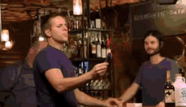 two men are shaking hands in a bar with a sign that says " refreshments daily "
