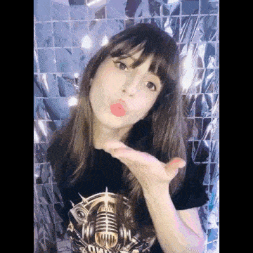 a woman blowing a kiss with her hand in front of a microphone .