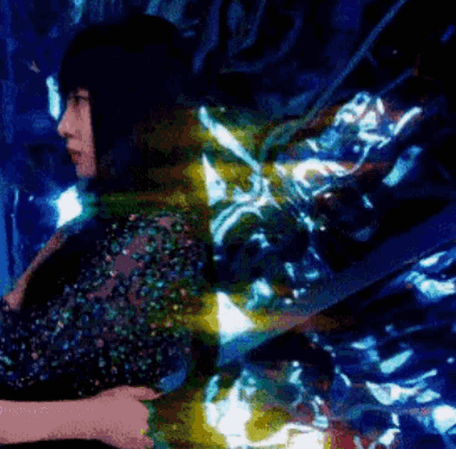 a woman is standing in a dark room with a blue background
