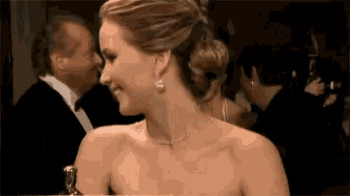 a woman in a strapless dress is smiling while holding an award .