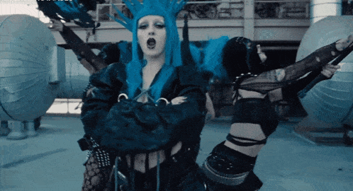 a woman with blue hair and a crown on her head stands in front of a group of people
