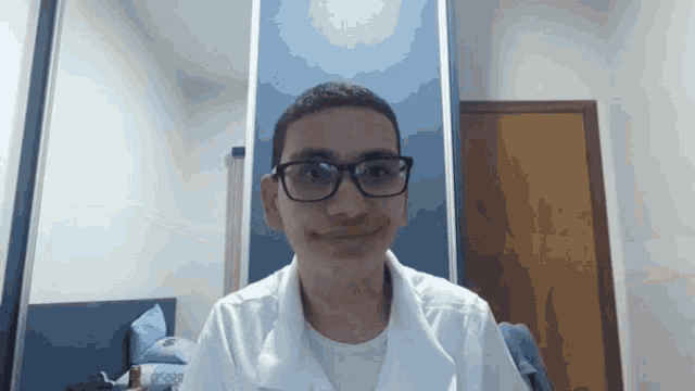 a young man wearing glasses and a white shirt smiles for the camera
