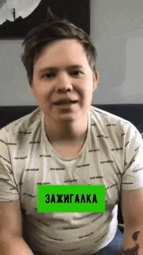 a man wearing a white t-shirt with a green sticker that says " zajigaaka "