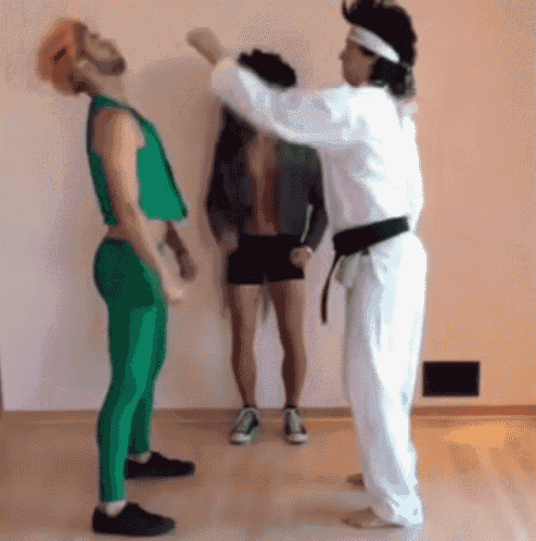a man in a white karate uniform is hitting another man in a green outfit