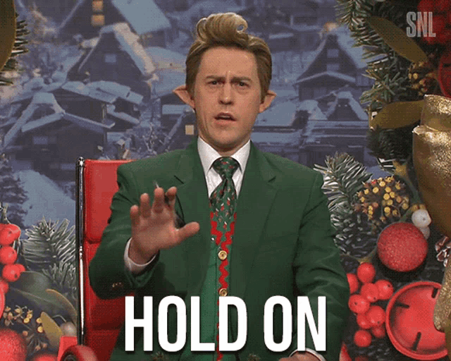 a man in a green suit and tie is making a hold on gesture