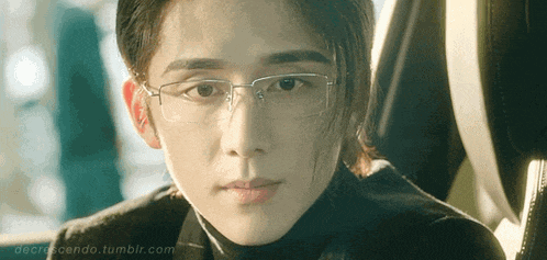 a man wearing glasses and a black turtleneck is looking at the camera