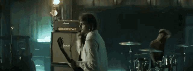 a man is playing a guitar in front of a marshall amp