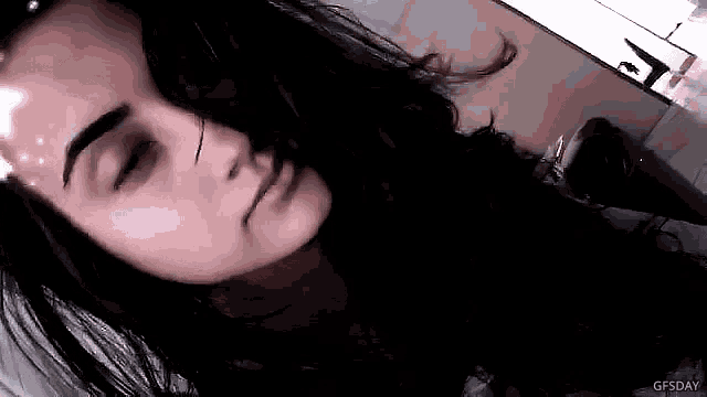a woman with long black hair is laying down with her eyes closed .