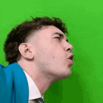 a man in a blue suit and tie is blowing a kiss against a green background .