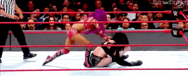 two women are wrestling in a wrestling ring with a referee watching .