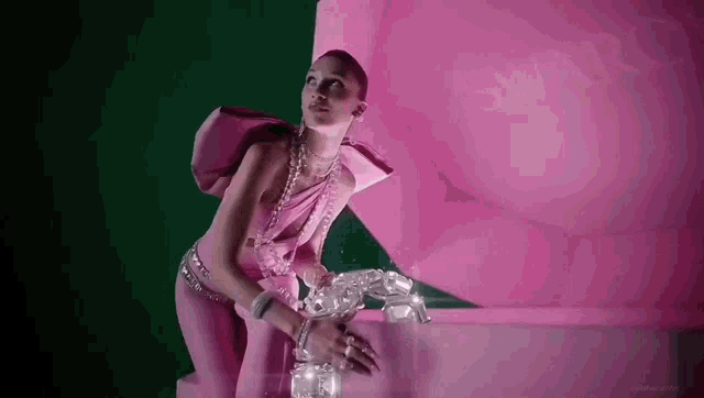 a woman in a pink dress is standing next to a pink box with a swarovski logo on it .