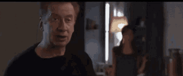 a man and a woman are standing in a room and the man is looking at the camera .