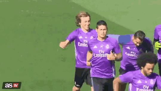 a group of soccer players are running on a field wearing purple jerseys that say fly emirates .