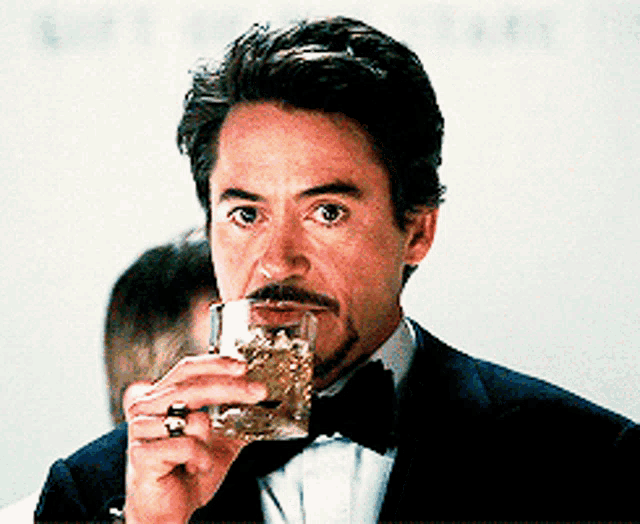 a man in a tuxedo drinking from a glass