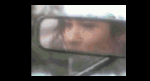 a woman is looking at herself in a rear view mirror