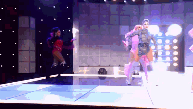 two drag queens are dancing on a stage and one is wearing a pink outfit