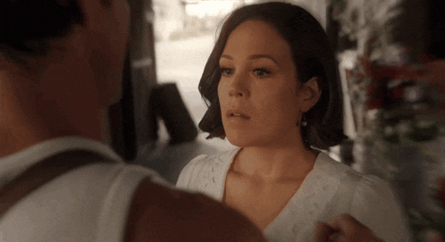 a woman in a white shirt is looking at a man