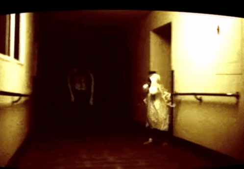 a person in a white coat is standing in a dark hallway holding a stuffed animal