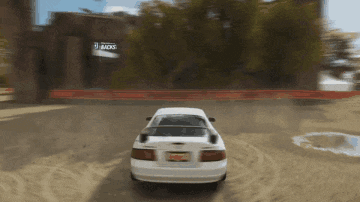 a white car is driving down a dirt road in front of a building that says ' jacks ' on it
