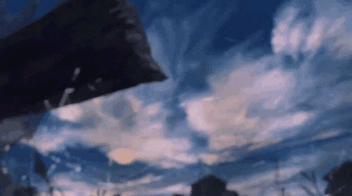 a person is standing in front of a blue sky with clouds and a flag in the foreground .