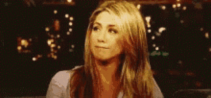 a woman with long blonde hair is making a funny face while sitting in a dark room .