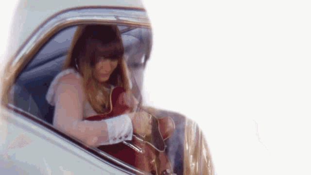 a man and a woman are sitting in a car looking out the window .