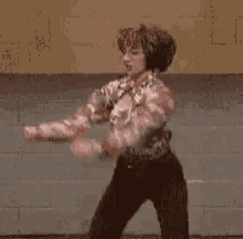 a man is standing in front of a brick wall wearing headphones and dancing .