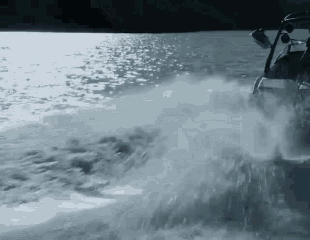 a black and white photo of a person driving a boat on a lake .
