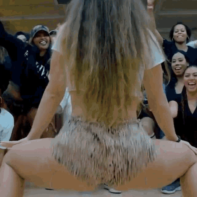 a woman is doing a butt flip in front of a group of people